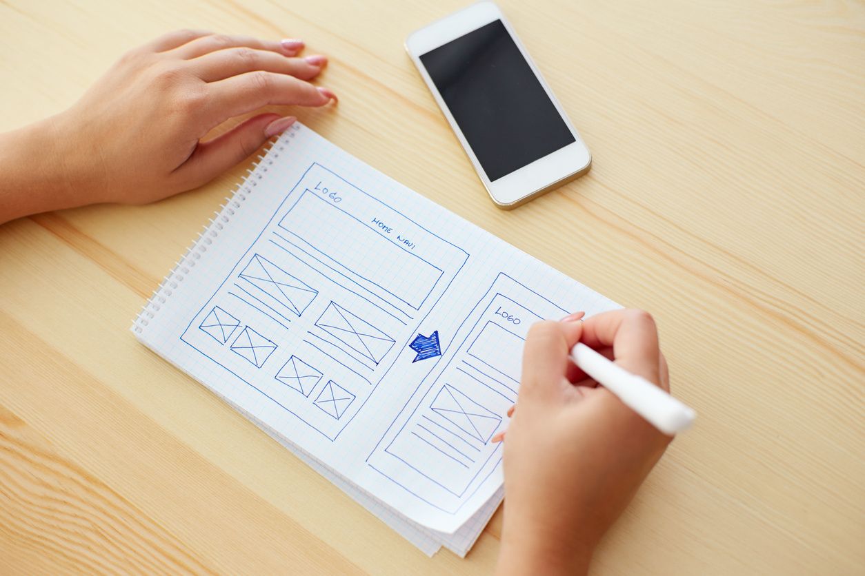 Hand-drawn website wireframe and smartphone on a desk